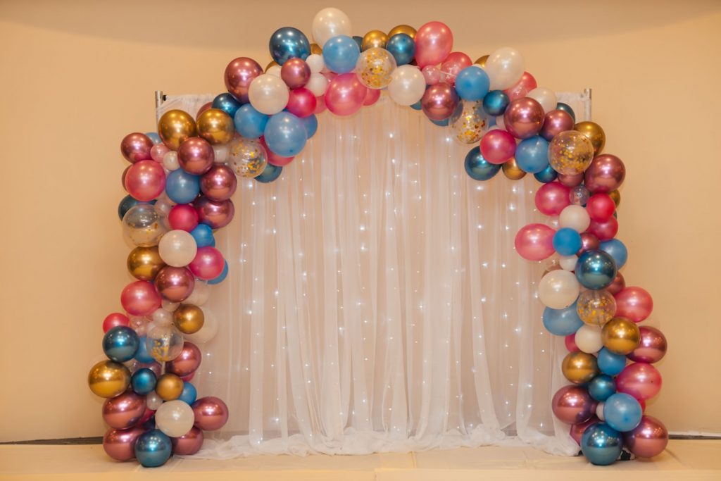 bogen aus bunten ballons und dahinter eine weiße gardine