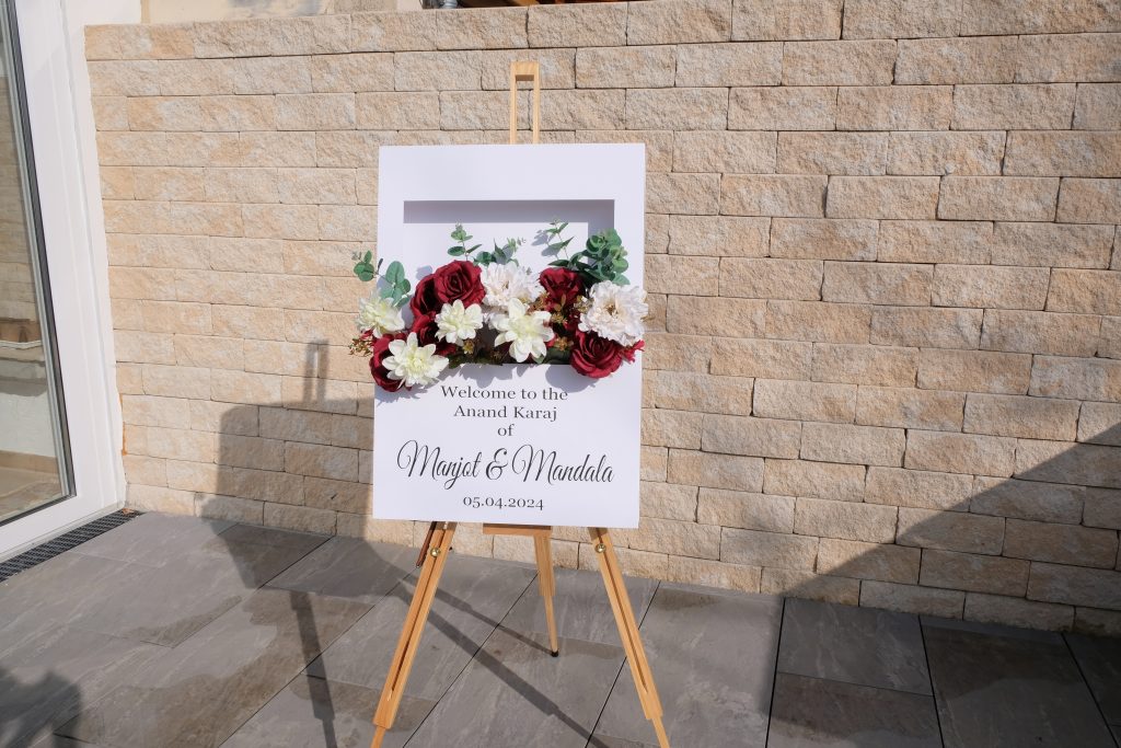 Auf einem Stativ stehendes in 3D aussehende Polaroid Box mit blumen im aussschnitt. unten drunter steht willkommen zur hochzeit von merve und Paul